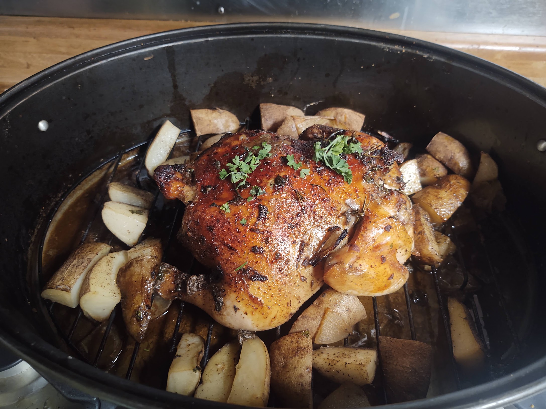 image of a whole baked chicken, potatoes are strewn about below it